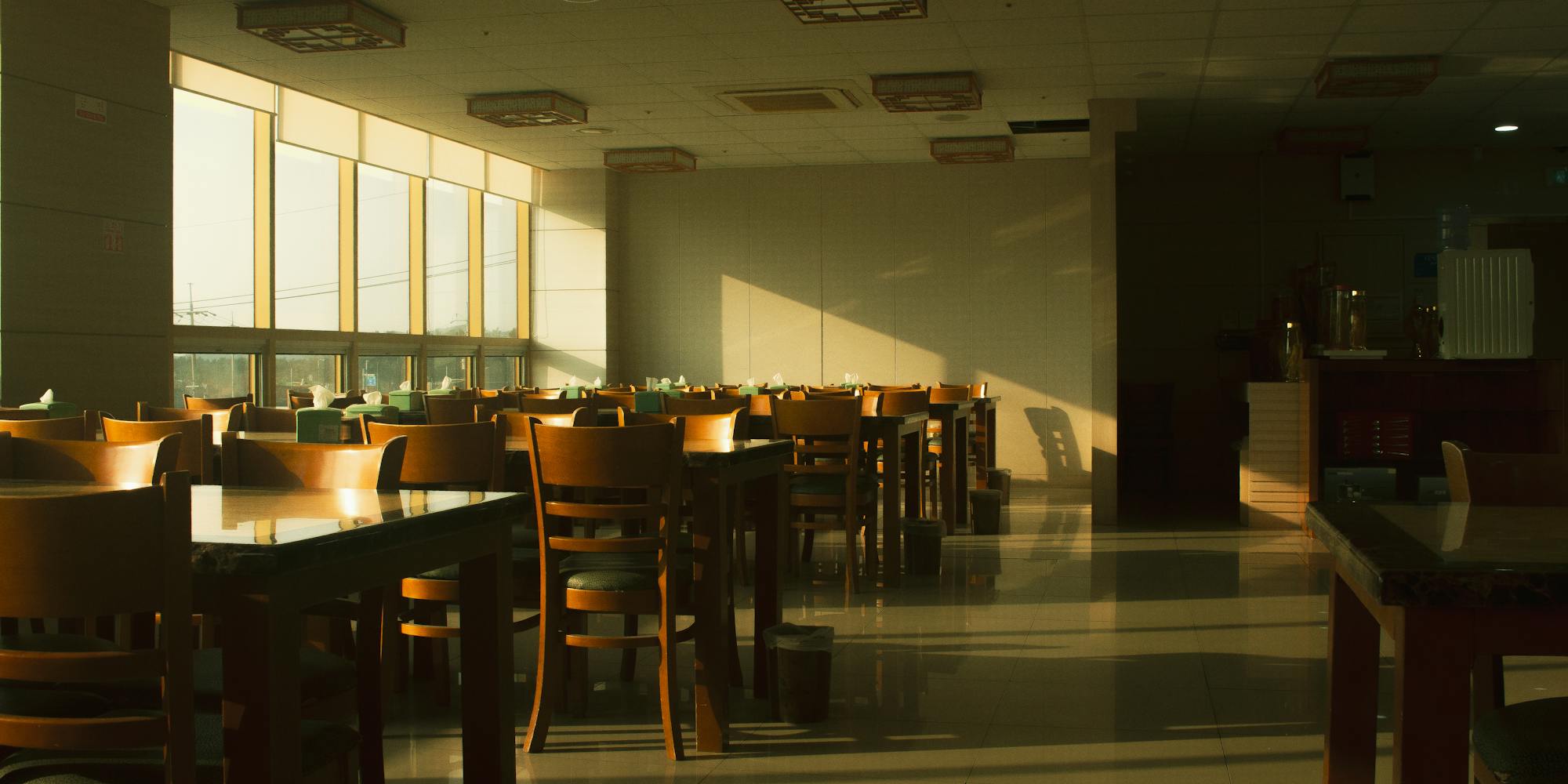 Empty restaurant interior with wooden tables set for service